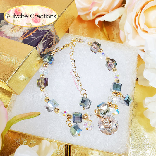 Cube crystal beaded bracelet with oval crystal charm on a decorative stand with flowers and 'Aulychei Creations' branding.